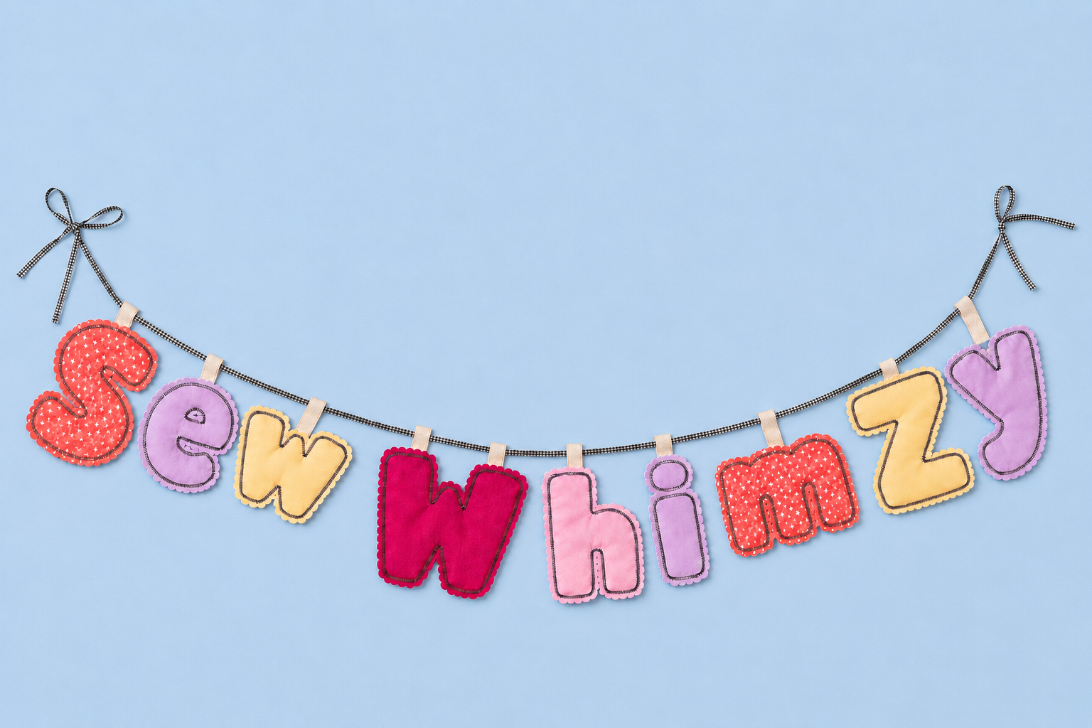 Hand-stitched felt letters spelling Sew Whimzy strung on black gingham ribbon with bows against a light blue background